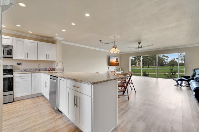 kitchen with white cabinets, a peninsula, ceiling fan, appliances with stainless steel finishes, and a sink