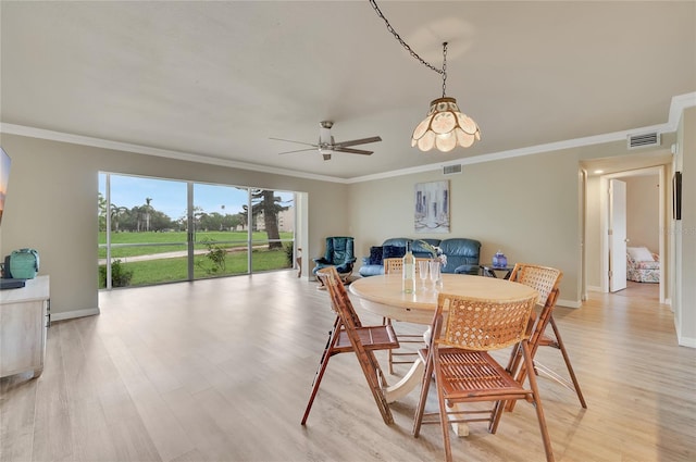 dining space with ornamental molding, light wood-style floors, ceiling fan, and visible vents