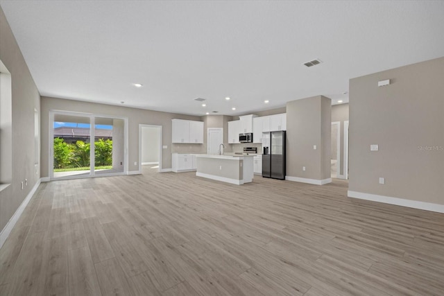 unfurnished living room with light hardwood / wood-style floors and sink