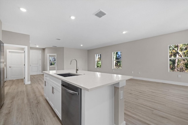 kitchen featuring light wood-type flooring, white cabinets, a kitchen island with sink, sink, and dishwasher