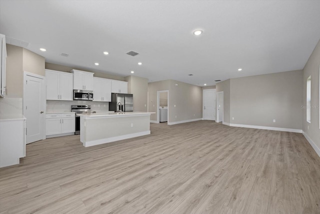 kitchen featuring decorative backsplash, an island with sink, light hardwood / wood-style floors, white cabinetry, and stainless steel appliances