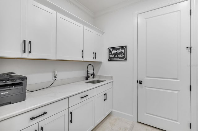 kitchen with sink, light stone counters, ornamental molding, and white cabinets