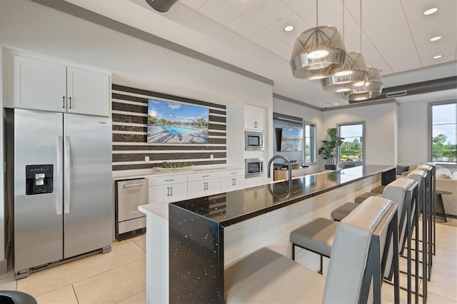 kitchen featuring appliances with stainless steel finishes, hanging light fixtures, a breakfast bar, and white cabinets