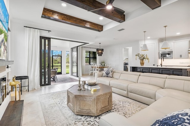 living room featuring beamed ceiling, sink, and light tile patterned floors