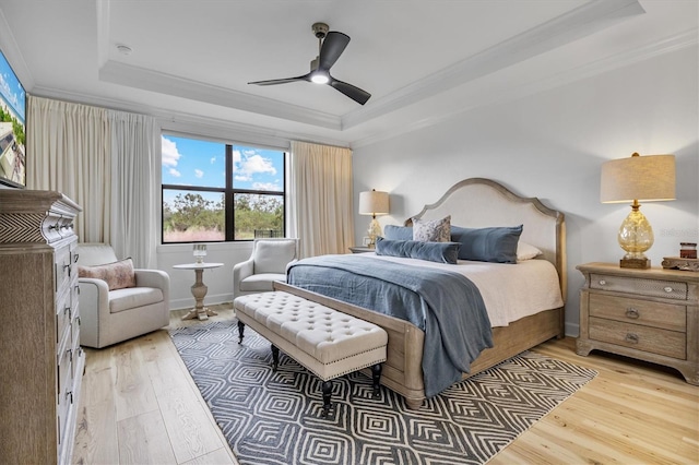 bedroom featuring a tray ceiling, multiple windows, and light hardwood / wood-style flooring