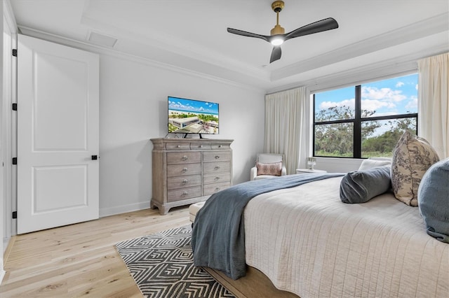 bedroom featuring ceiling fan, crown molding, light hardwood / wood-style floors, and a raised ceiling