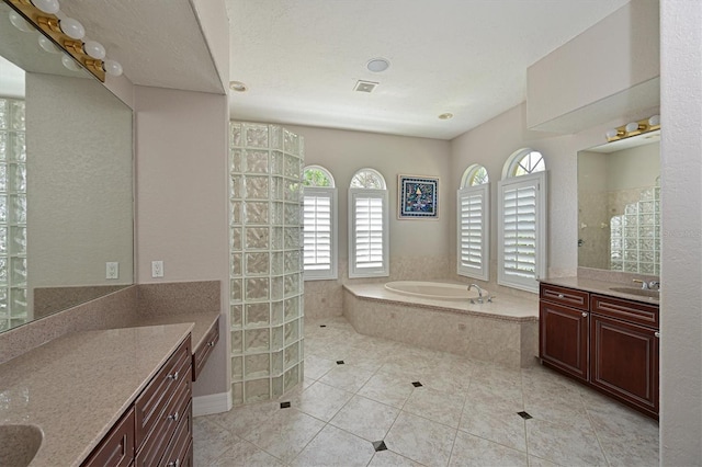 bathroom with plus walk in shower, a textured ceiling, vanity, and tile patterned floors