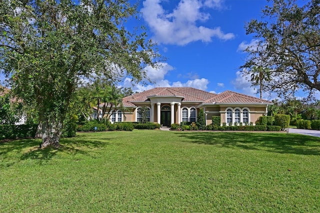 mediterranean / spanish-style house with a tile roof, a front yard, and stucco siding