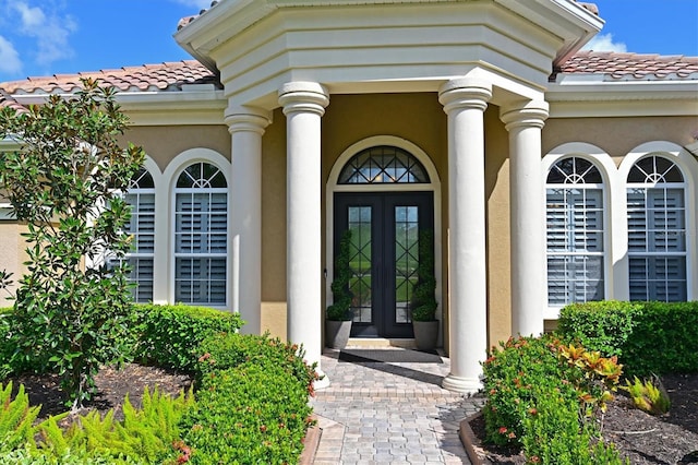 doorway to property with french doors, stucco siding, and a tiled roof