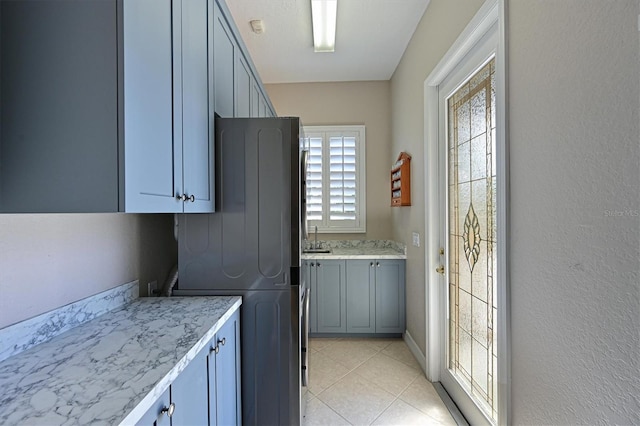 clothes washing area featuring light tile patterned floors, cabinet space, and a sink