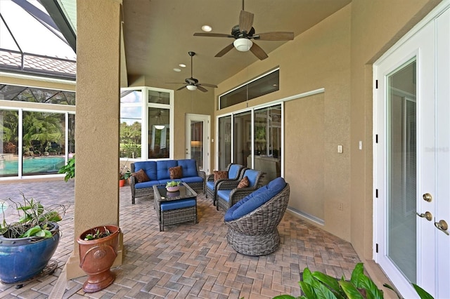 view of patio featuring glass enclosure, a ceiling fan, and outdoor lounge area