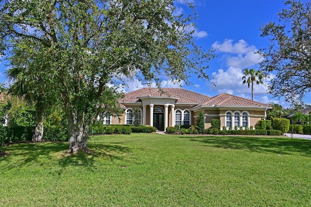 mediterranean / spanish house featuring stucco siding, a front lawn, and a tile roof