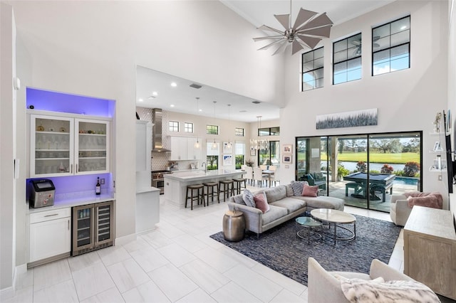 tiled living room featuring ceiling fan, a towering ceiling, and beverage cooler