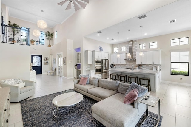 living room with ceiling fan with notable chandelier, light tile patterned floors, and a towering ceiling