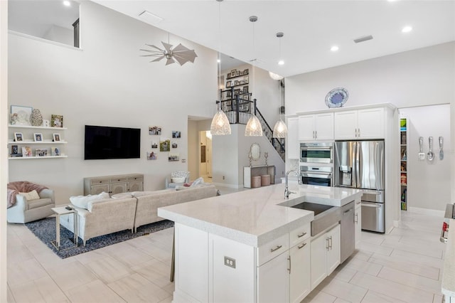 kitchen with a center island with sink, white cabinetry, sink, and appliances with stainless steel finishes