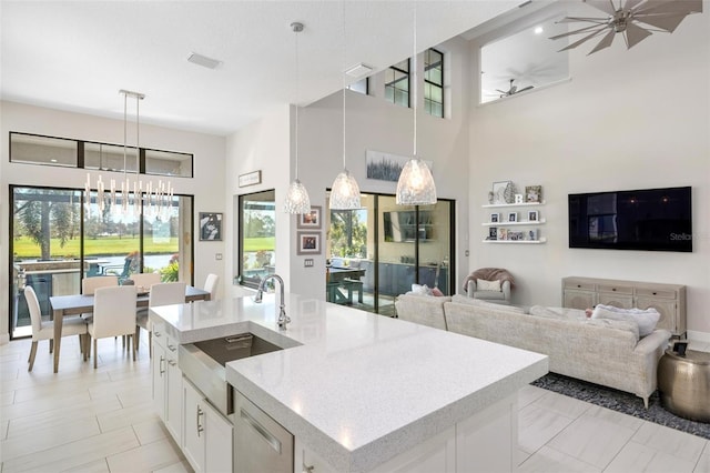 kitchen with sink, pendant lighting, a high ceiling, white cabinetry, and an island with sink