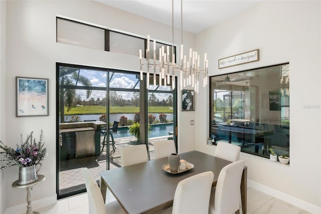 dining space featuring a chandelier, light tile patterned floors, a water view, and plenty of natural light