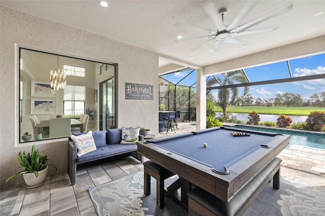 rec room with a textured ceiling, ceiling fan with notable chandelier, a water view, and billiards