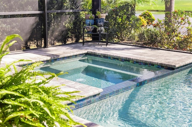 view of pool with an in ground hot tub and glass enclosure