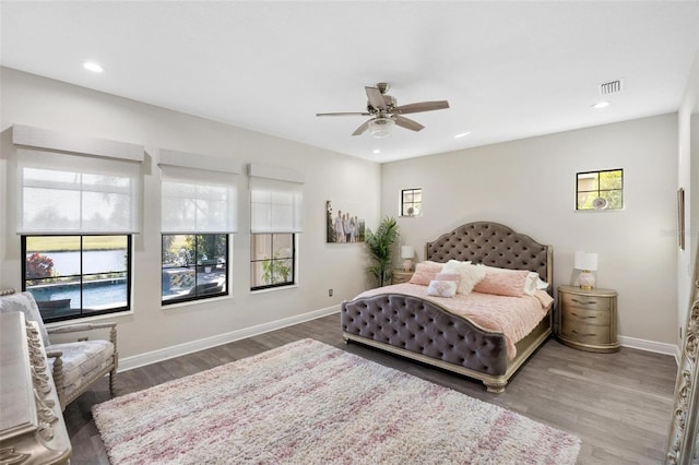 bedroom with ceiling fan, dark wood-type flooring, and multiple windows