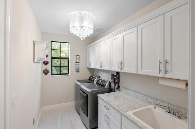 laundry room with washer and clothes dryer, cabinets, sink, and a textured ceiling