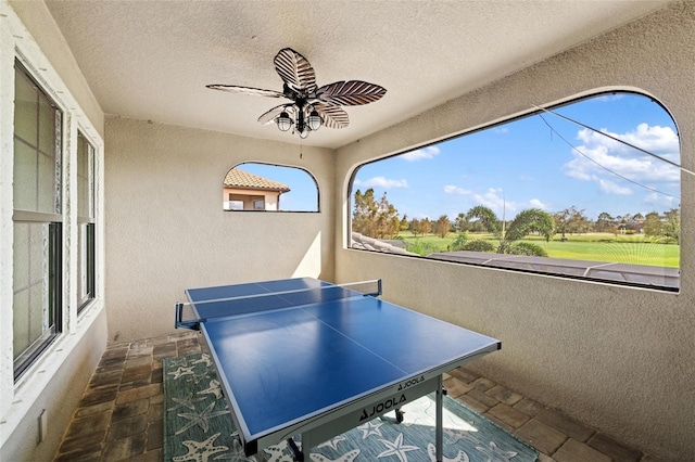 game room with ceiling fan and a textured ceiling