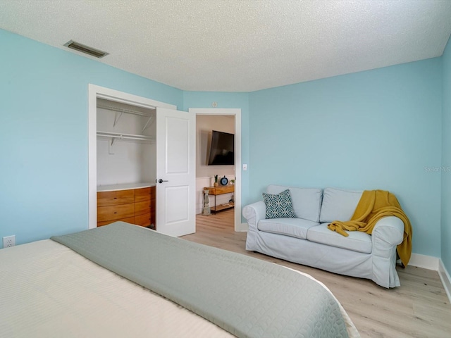 bedroom with a closet, a textured ceiling, and light hardwood / wood-style flooring