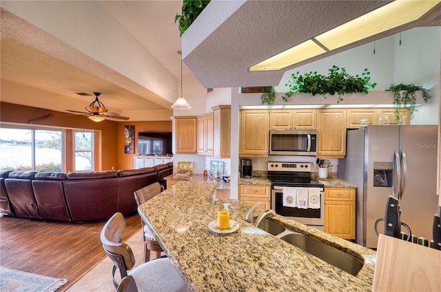 kitchen featuring light wood-type flooring, stainless steel appliances, a textured ceiling, and decorative light fixtures