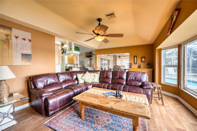 living room featuring ceiling fan, vaulted ceiling, a healthy amount of sunlight, and light hardwood / wood-style flooring