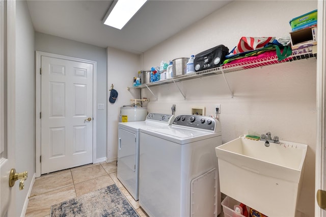 laundry area with secured water heater, washer and clothes dryer, sink, and light tile patterned floors