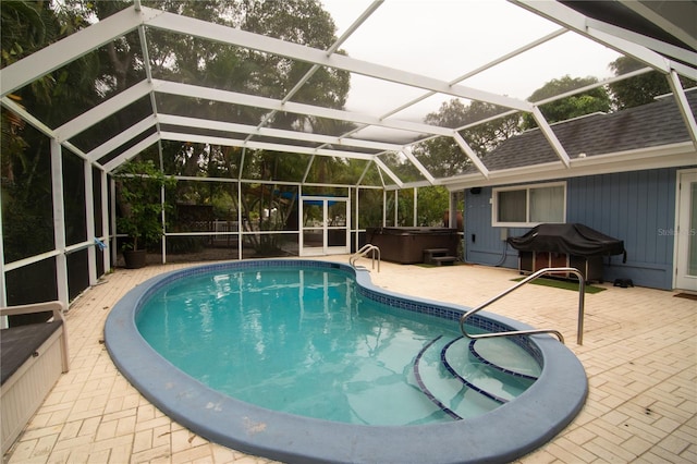 view of swimming pool with grilling area, glass enclosure, a hot tub, and a patio area