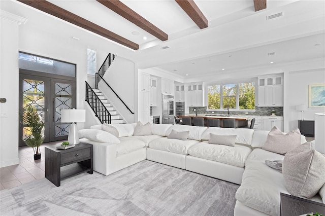 tiled living room with french doors, ornamental molding, and beam ceiling