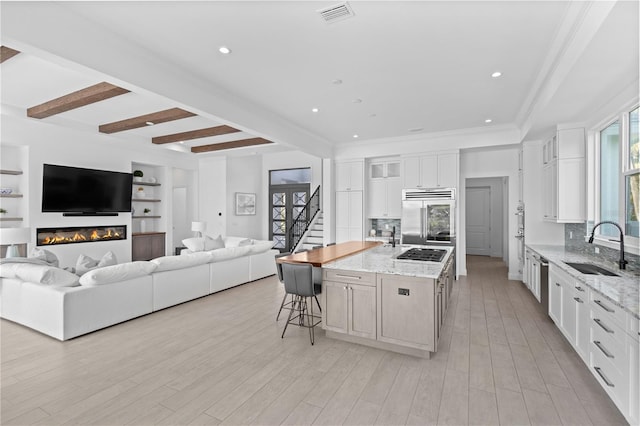 kitchen featuring white cabinetry, stainless steel appliances, sink, and an island with sink