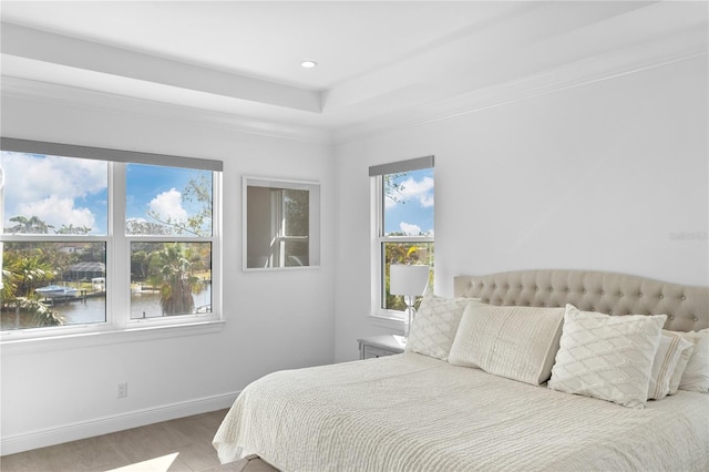 bedroom with ornamental molding, a water view, and hardwood / wood-style flooring