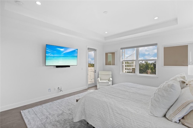 bedroom with access to exterior, dark hardwood / wood-style flooring, and a raised ceiling