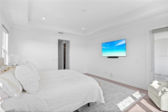 bedroom featuring light hardwood / wood-style floors, crown molding, and a tray ceiling