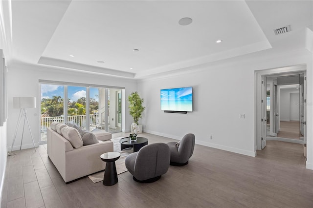 living room featuring light wood-type flooring and a tray ceiling