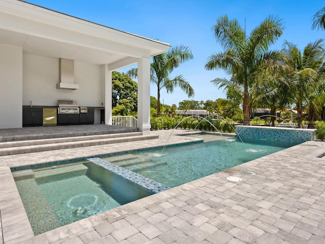 view of pool featuring an in ground hot tub, a patio, area for grilling, pool water feature, and an outdoor kitchen