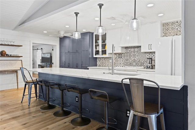 kitchen with a kitchen bar, light stone counters, a barn door, white fridge, and decorative light fixtures