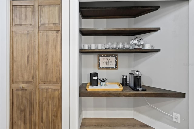 bar featuring dark wood-type flooring and light brown cabinetry