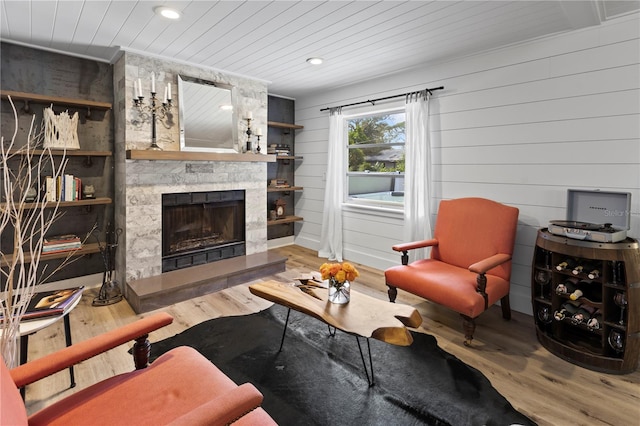 living room featuring a stone fireplace, hardwood / wood-style floors, wood walls, and wood ceiling