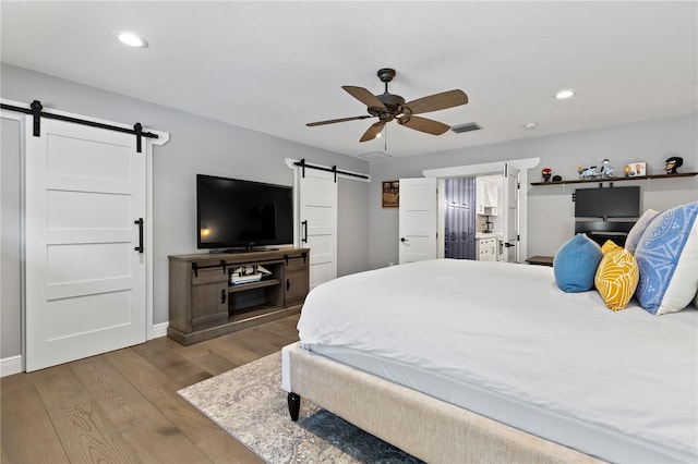 bedroom with light hardwood / wood-style flooring, a barn door, and ceiling fan