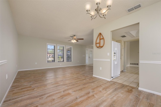 unfurnished living room with ceiling fan with notable chandelier, light wood-type flooring, and a textured ceiling