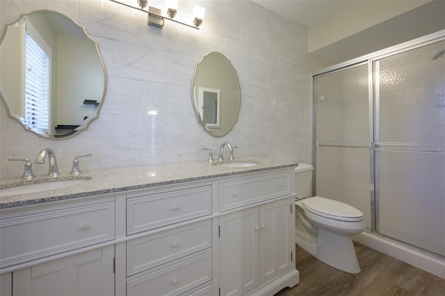 bathroom featuring hardwood / wood-style floors, backsplash, a shower with door, and tile walls