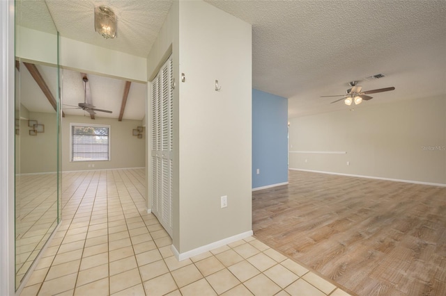 hall featuring vaulted ceiling with beams, a textured ceiling, and light wood-type flooring