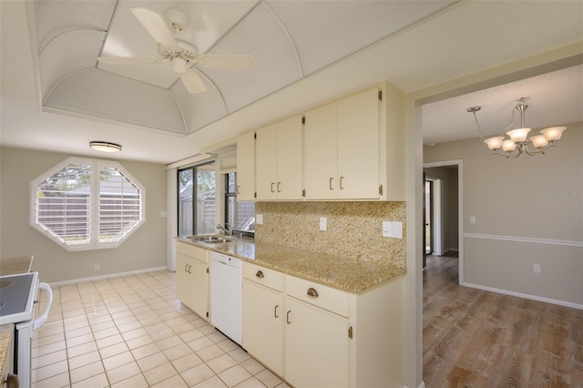 kitchen with decorative backsplash, light stone counters, white dishwasher, sink, and stainless steel stove