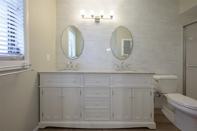 bathroom featuring vanity, a shower with door, hardwood / wood-style flooring, tile walls, and toilet