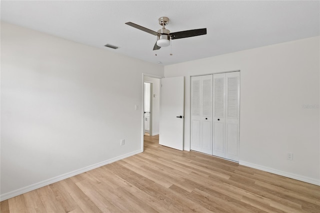 unfurnished bedroom with ceiling fan, light wood-type flooring, and a closet