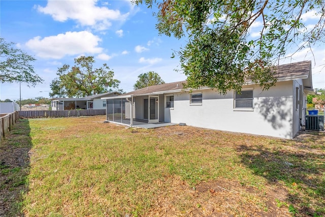 rear view of property with central AC, a sunroom, and a yard