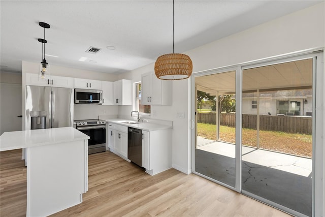 kitchen with pendant lighting, stainless steel appliances, white cabinetry, and sink